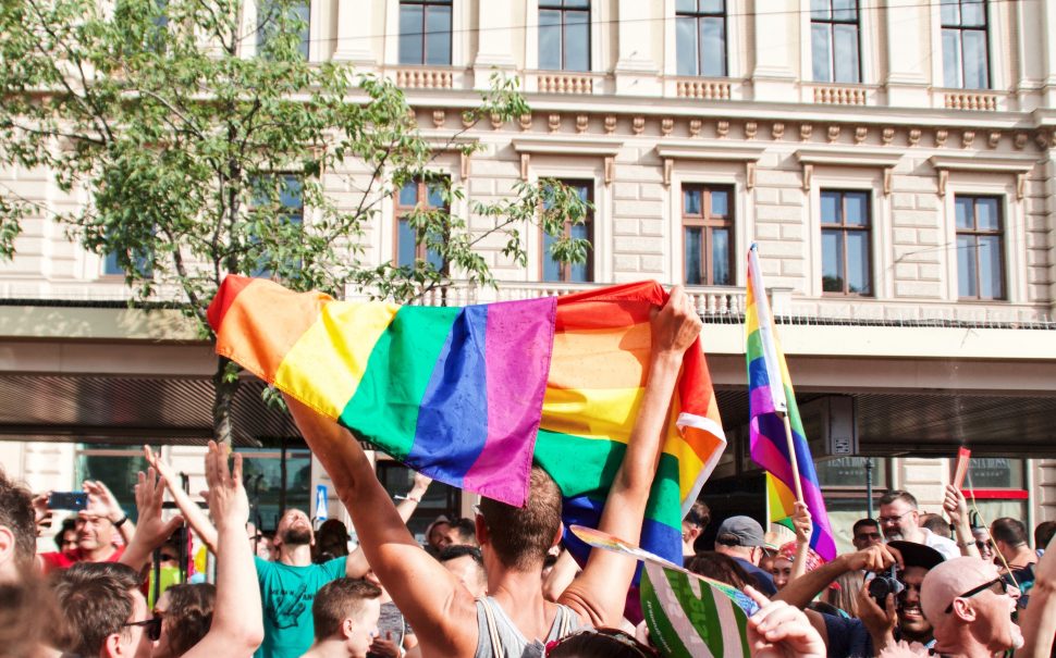 Man holding LGBT pride flag in crowd