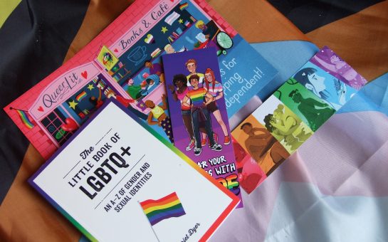 A flat lay of some items from Queer Lit bookshop in Manchester, including a bookmark, a book and a flyer