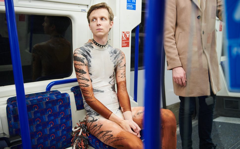 Photo of Linus Karp sitting dressed in a full Cats-style Jellicle body suit on the London Underground