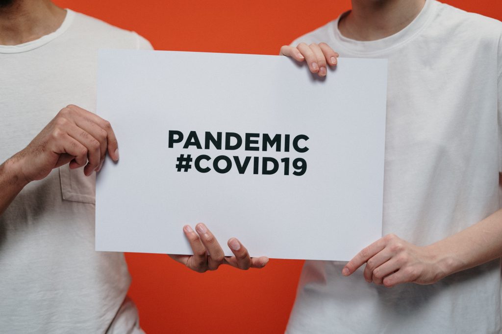people holding sign that says 'pandemic covid19'