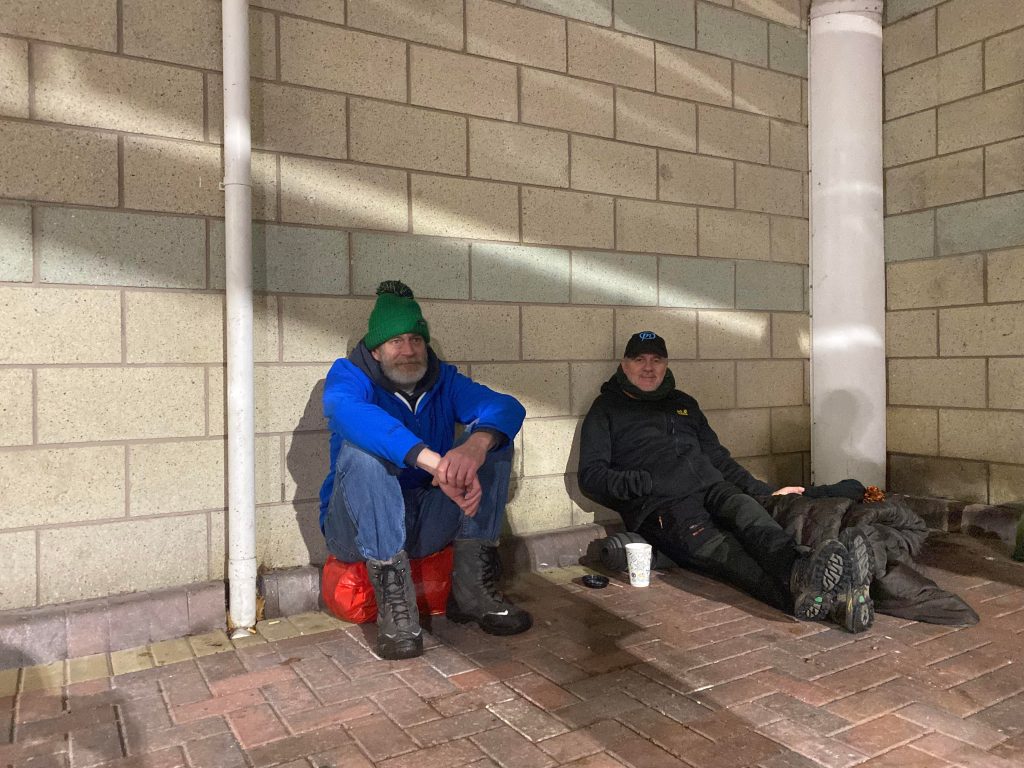Two men participating in the sleepout organised by Bury Homeless Project sat against a wall