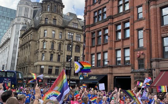 A crowd of people waving flags at Manchester Pride 2022