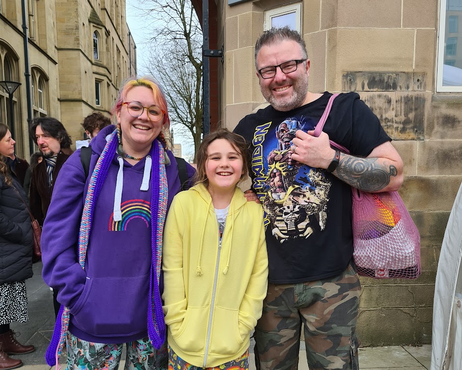 A young girl and her mother and father queueing outside Manchester Museum
