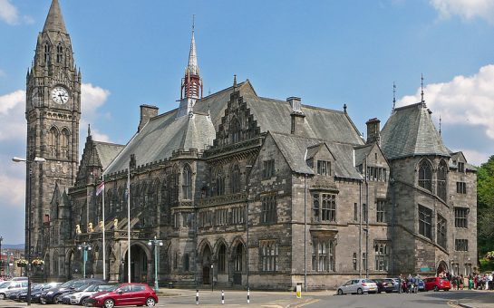 A picture of the Rochdale Town Hall on a sunny day, featuring the clock tower on the left side.