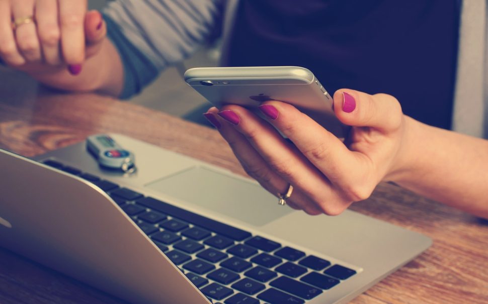 A person holding a phone over a laptop