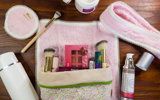 A flat lay image of beauty products in a makeup bag including brushes and palettes