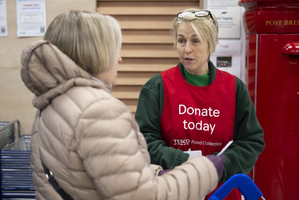 Food donations volunteer at Tesco talking to customer