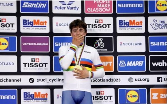 Archie Atkinson looks shocked standing in his rainbow jersey with his gold medal