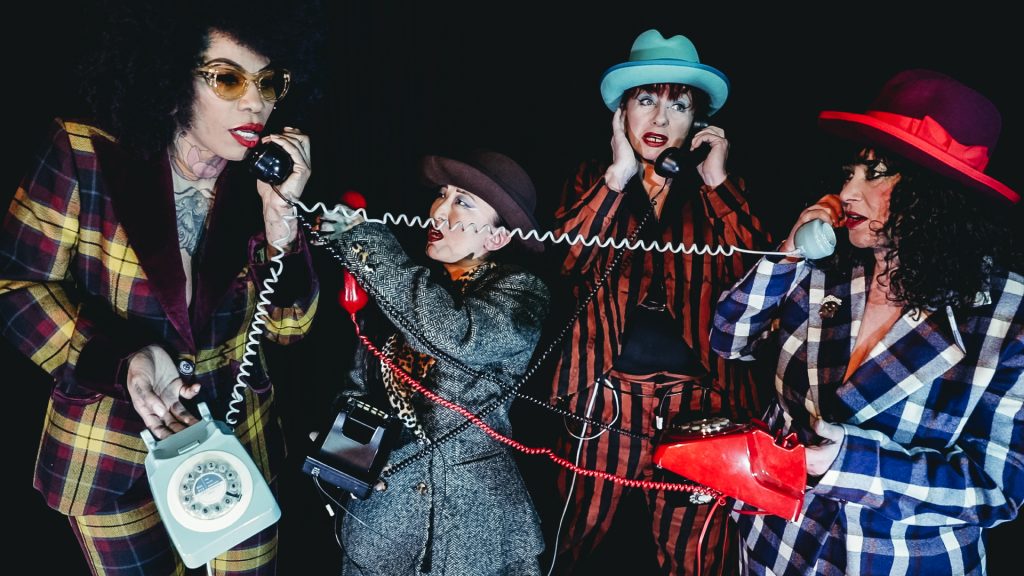 Four women using a telephone