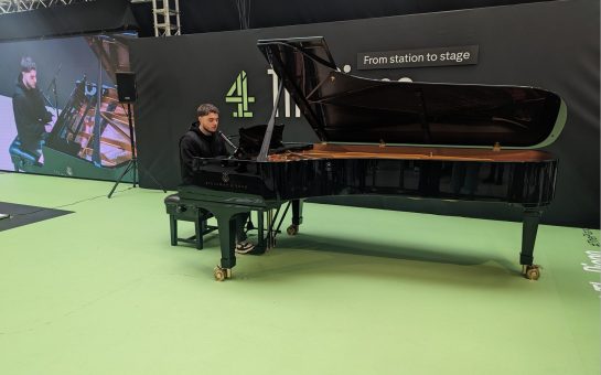 Daniel Wilsher playing a black Steinman and Sons piano on a green floor with screen and C4 logo in background