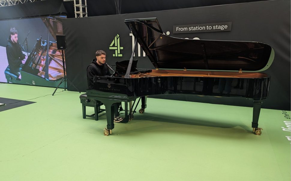 Daniel Wilsher playing a black Steinman and Sons piano on a green floor with screen and C4 logo in background