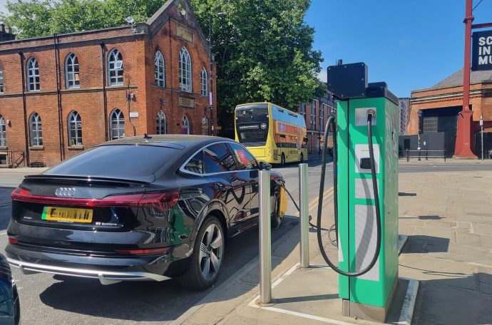A black car is plugged into a public electric vehicle charger.