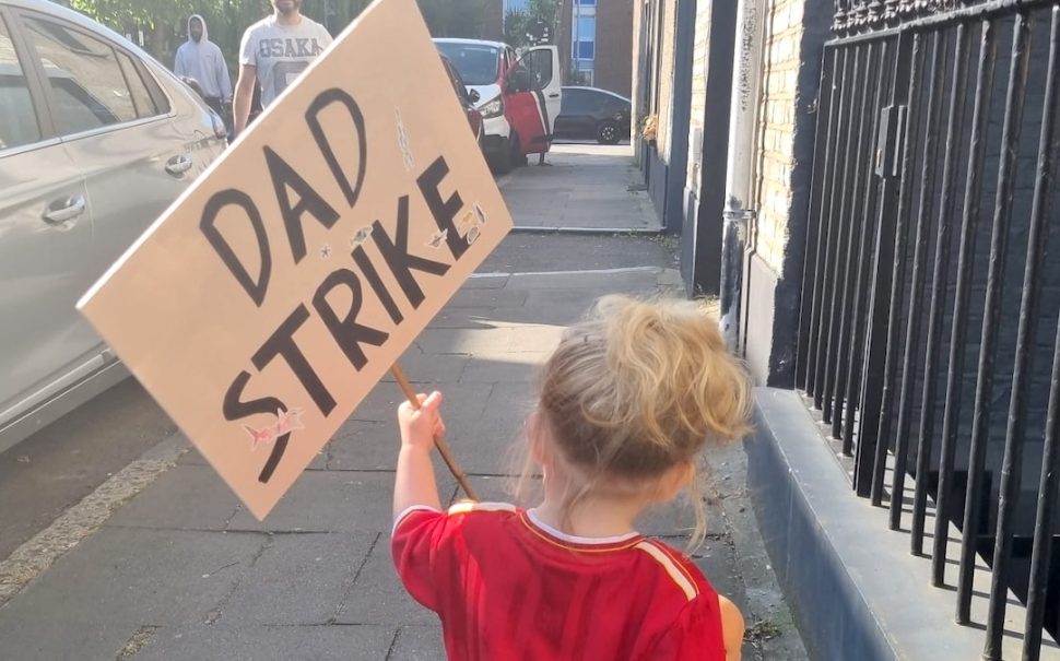 A young girl holding a placard that reads DAD STRIKE