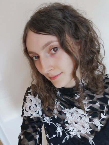 A selfie of Elaina Knibb, 28, who has long dark hair and is smiling at the camera. 