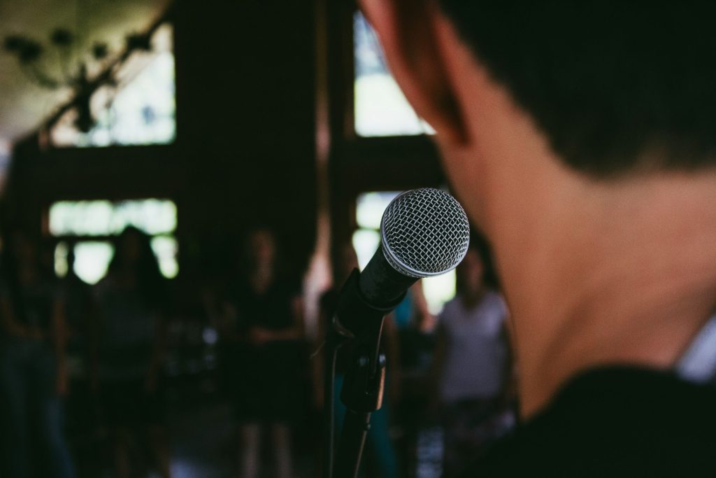 A man speaks into a microphone in front a group of people.
