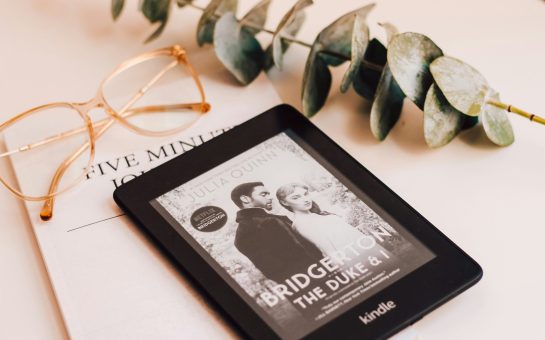 A photo of Bridgerton's The Duke and I on a kindle surrounded by an aesthetic piece of shrubbery and a bow