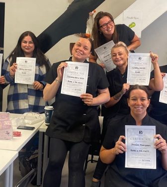 Manchester-based Feel Good Futures Training CIC. A group of female trainees holding up their certificates earned proudly.