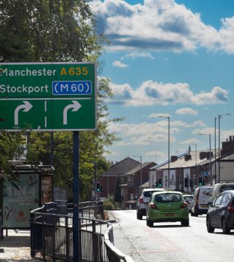 A picture of a Stockport sign, a road and housing
