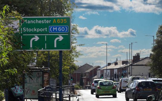 A picture of a Stockport sign, a road and housing