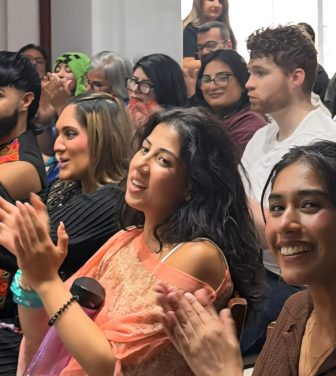 An image of the audience at the SamajhMyGal open mic event. The audience are clapping with some members of the audience looking at the camera.