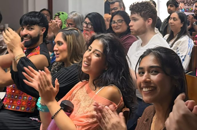 An image of the audience at the SamajhMyGal open mic event. The audience are clapping with some members of the audience looking at the camera.